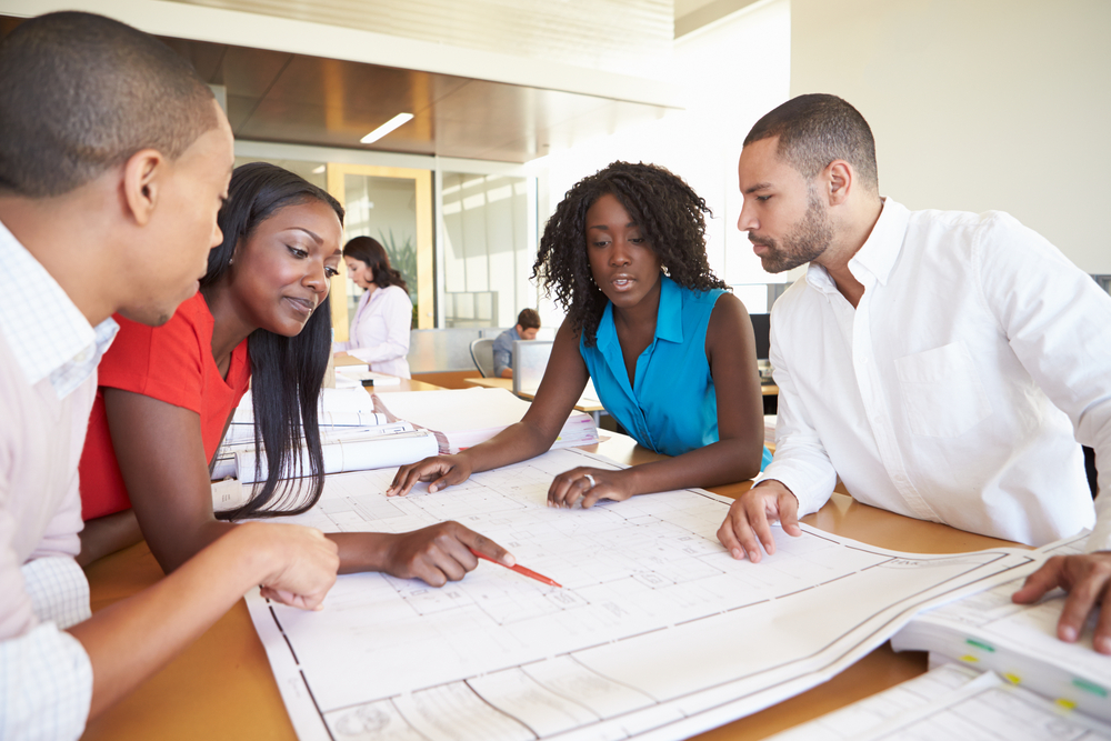 People sitting at a table looking at a document and discussing it